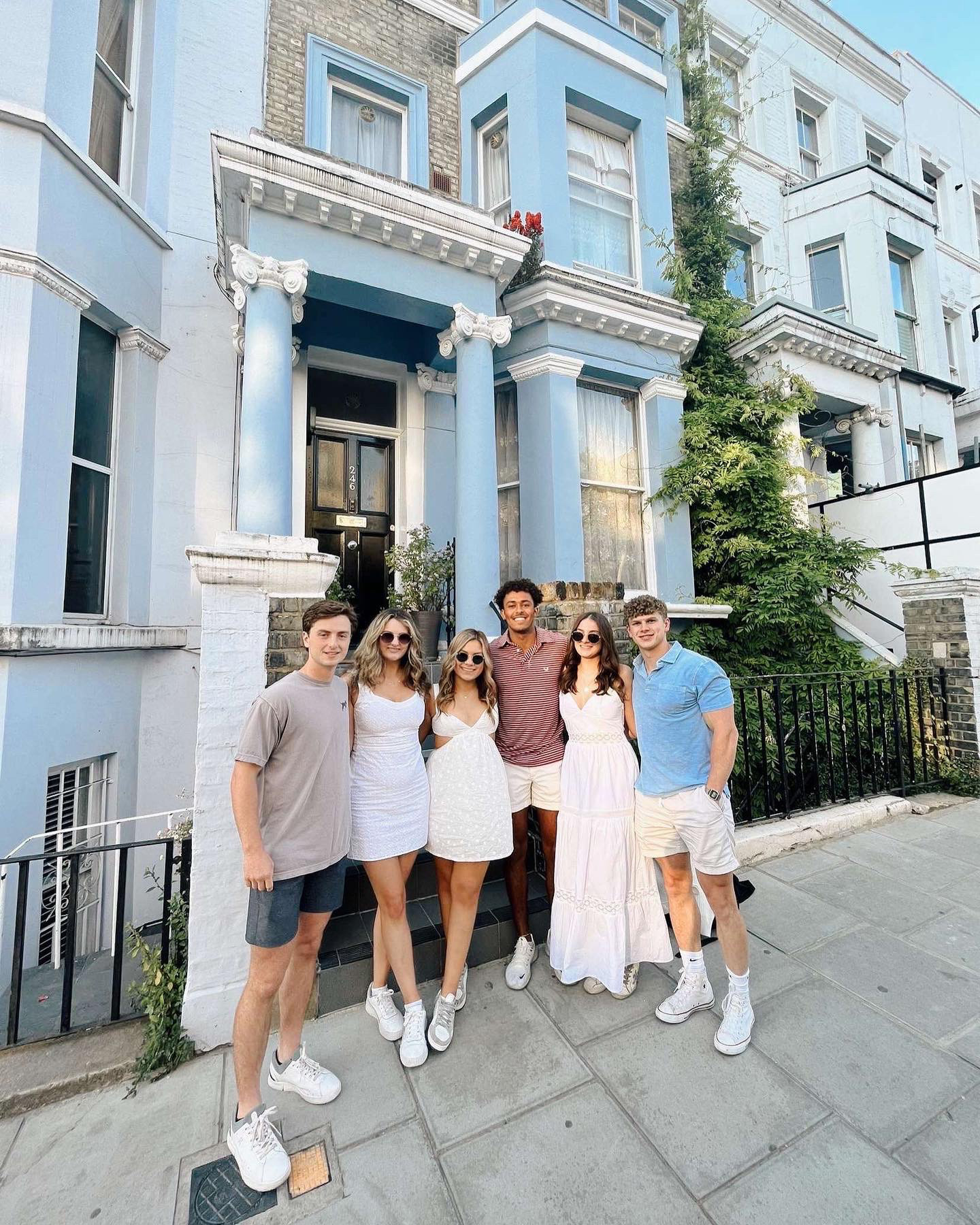 Six students posing in front of brightly colored town homes in London
