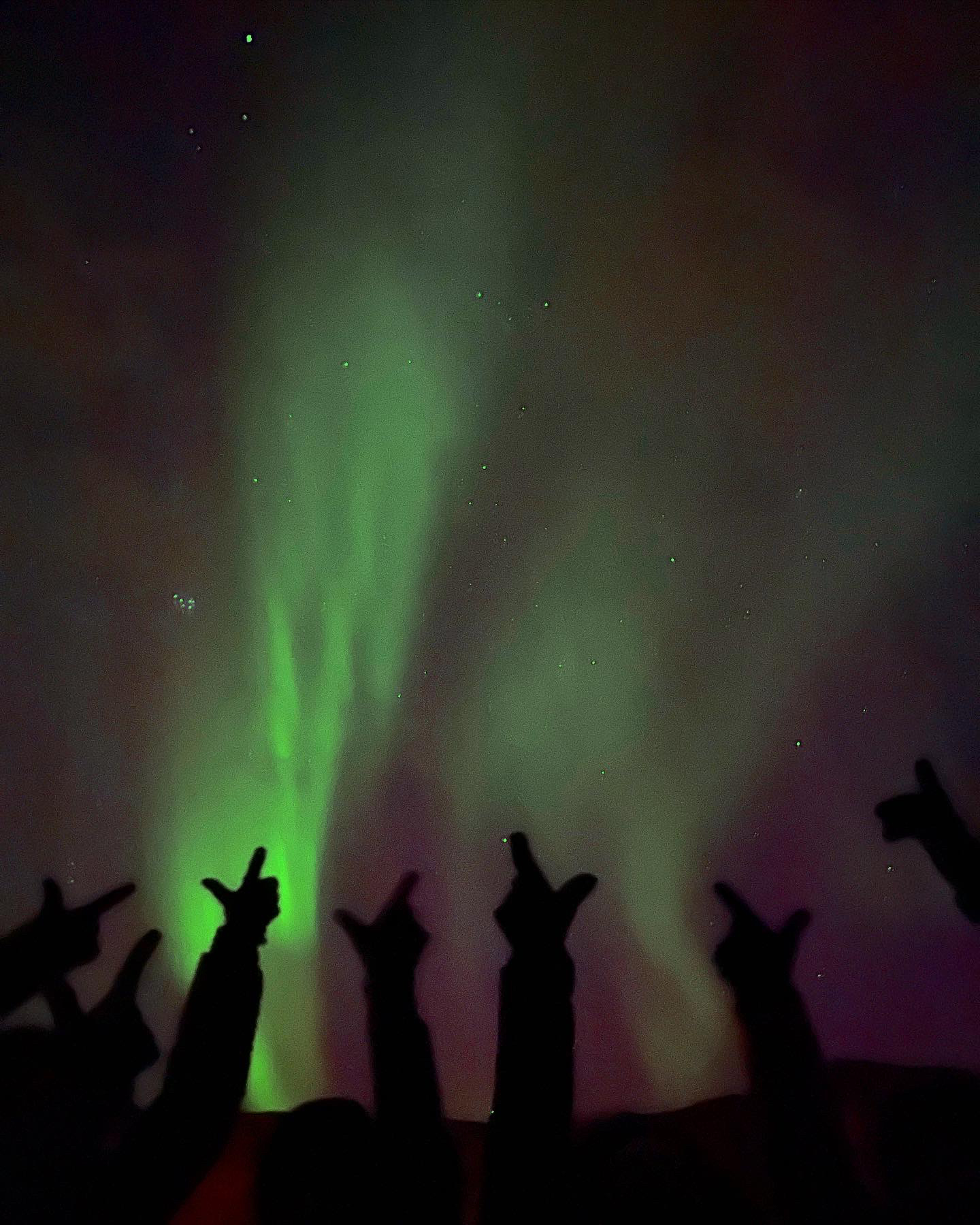 Students holding up "go pokes" sign in front of Northern Lights