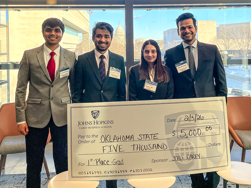 Four business students receive an oversized check.