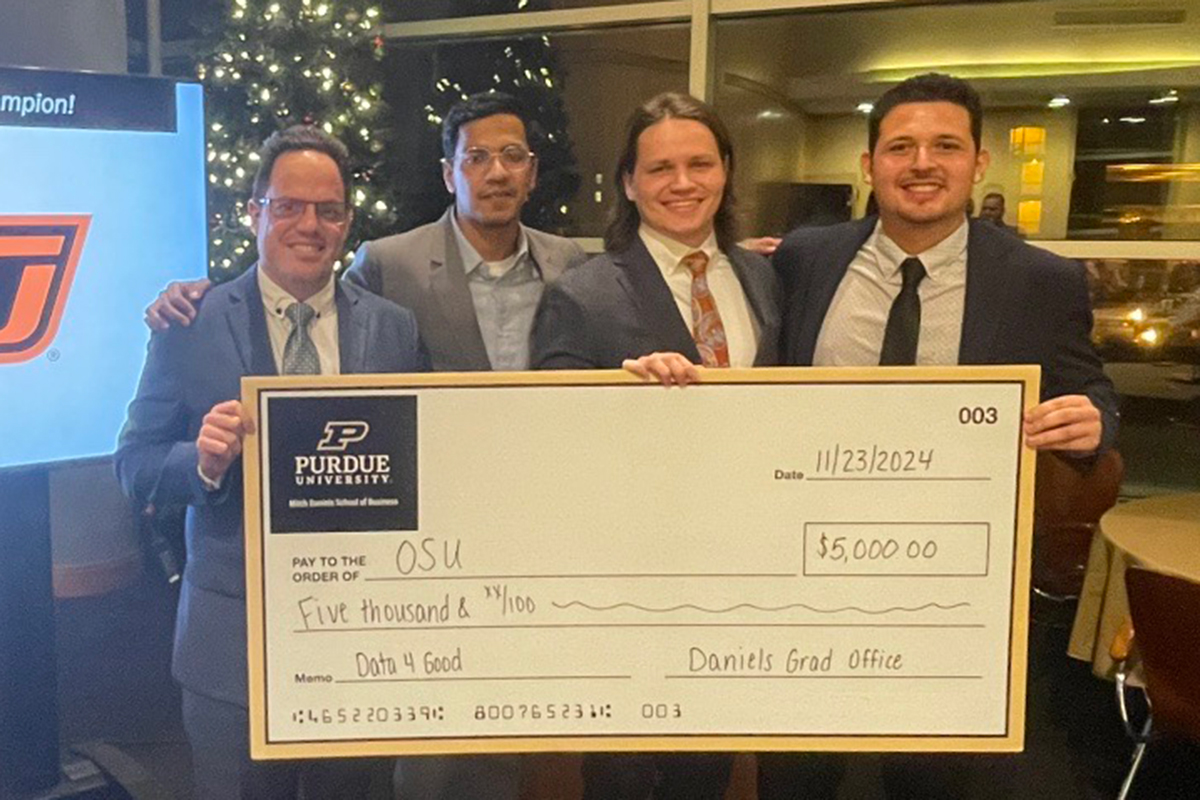 Data 4 Good Four MS BAnDS students hold an oversized check after winning the Data 4 Good competition.