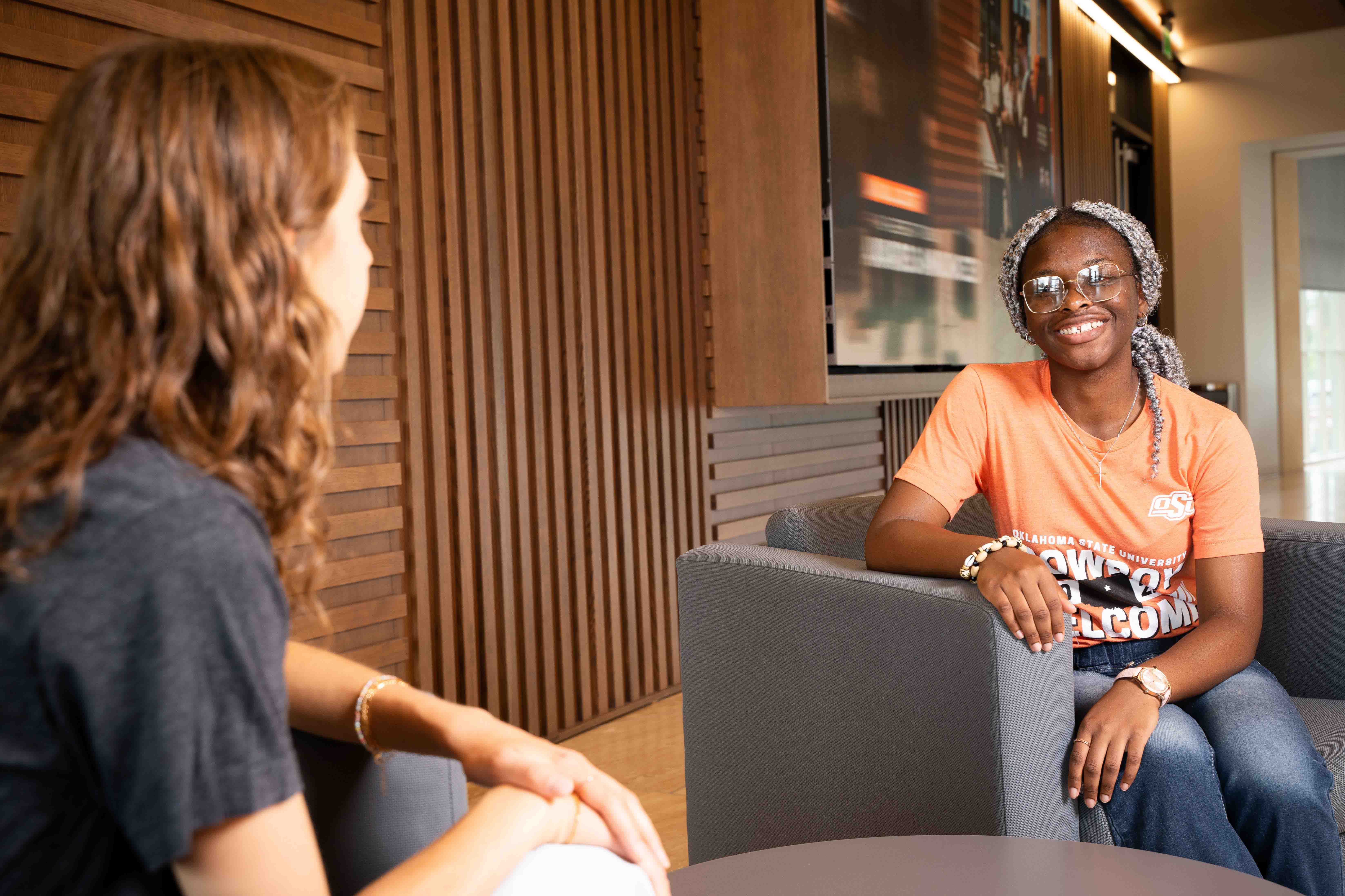 Two female students sitting in chairs talking