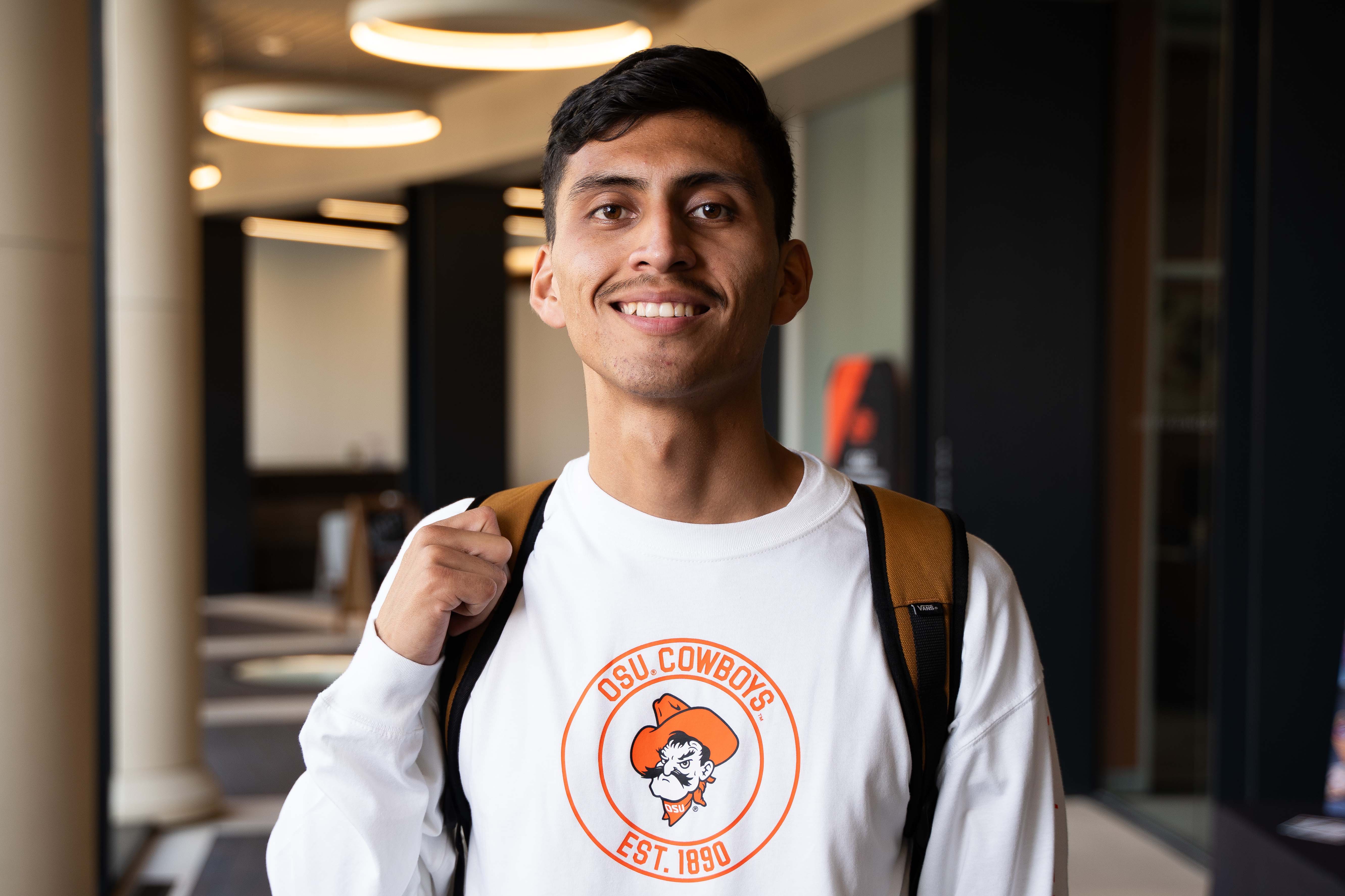 Student smiling with backpack on in the Spears hallway
