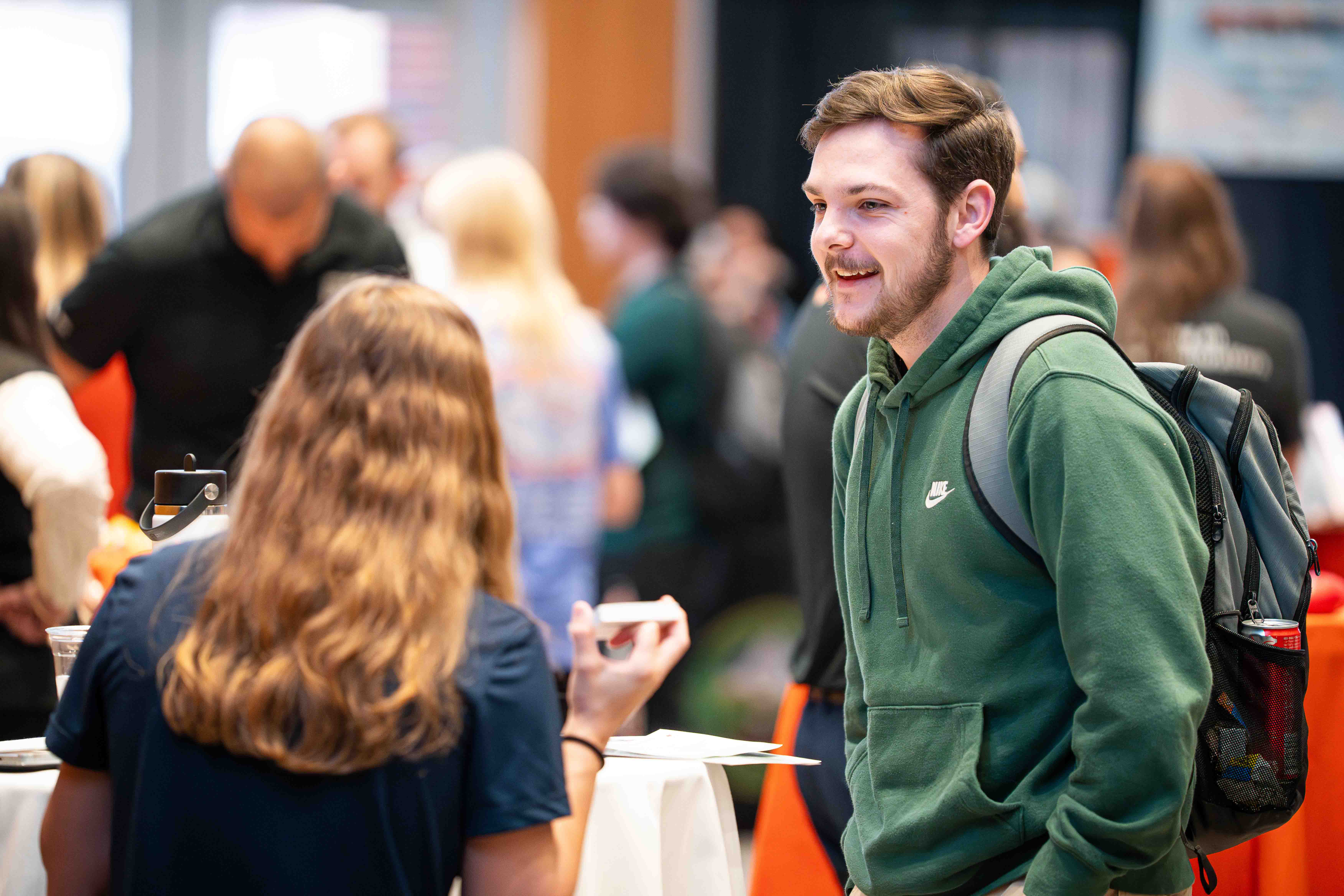 Male student dressed casually smiling while having a conversation