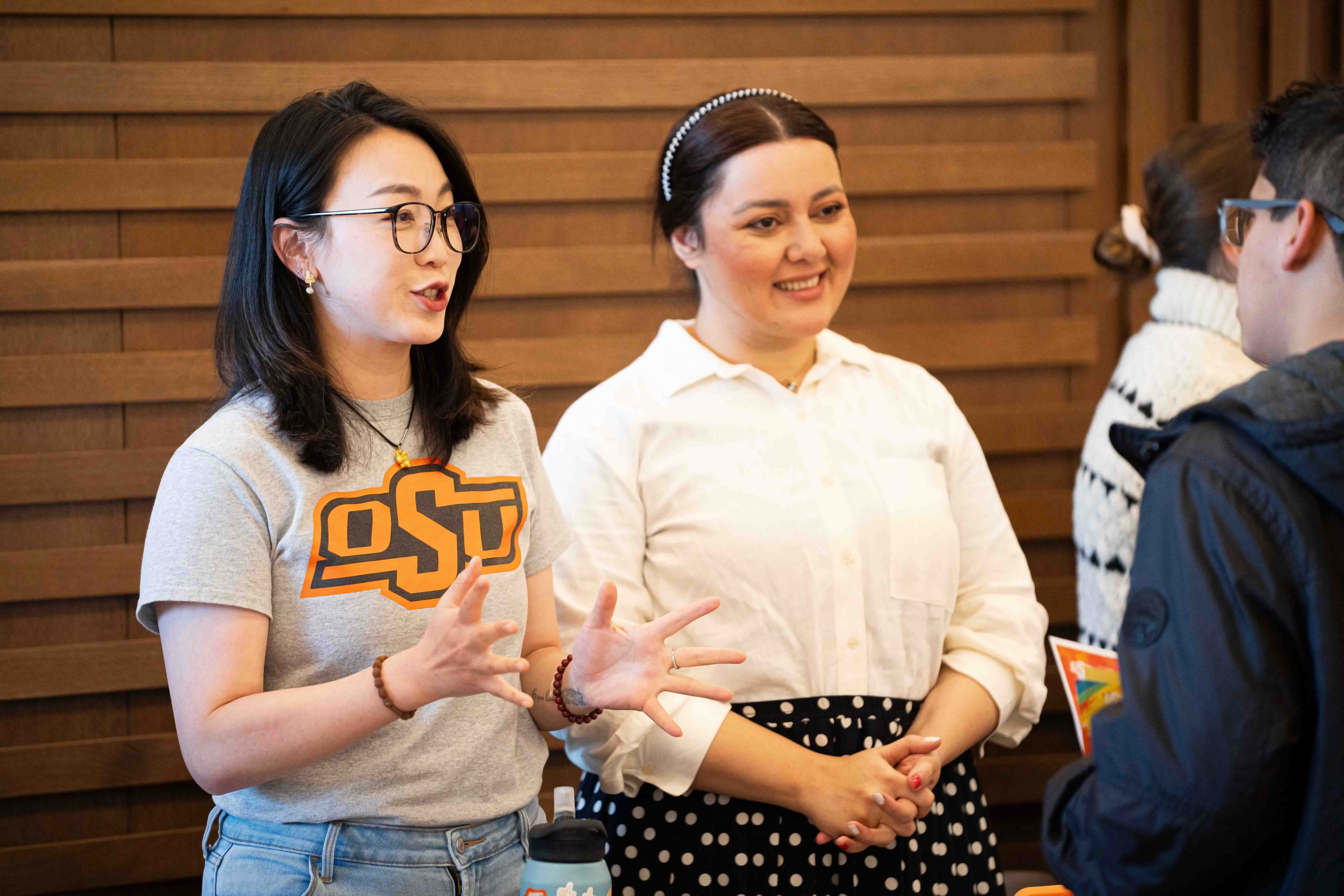 Two female students speaking to a male student a club fair
