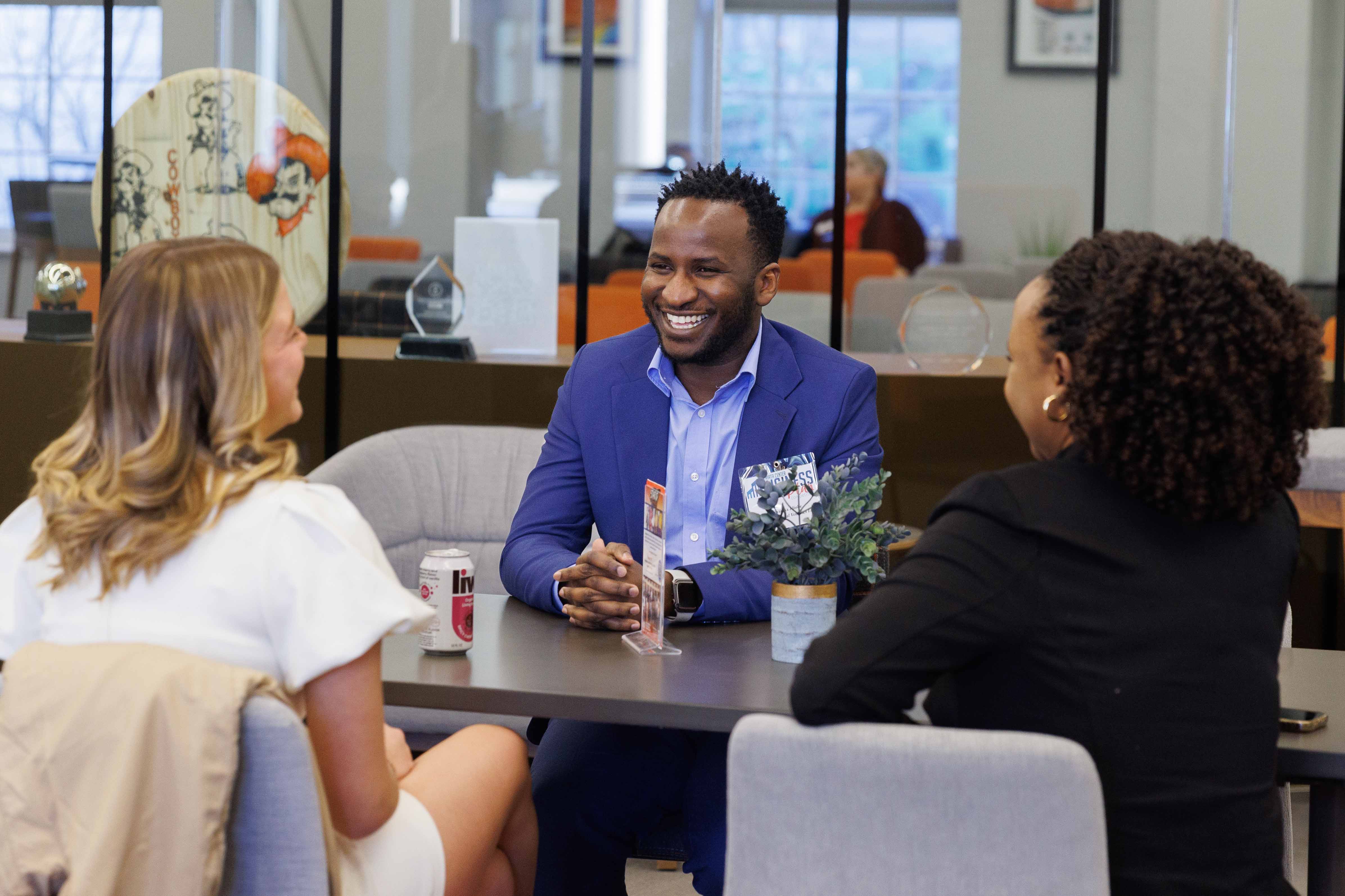 Three students smiling and speaking dressed professionally