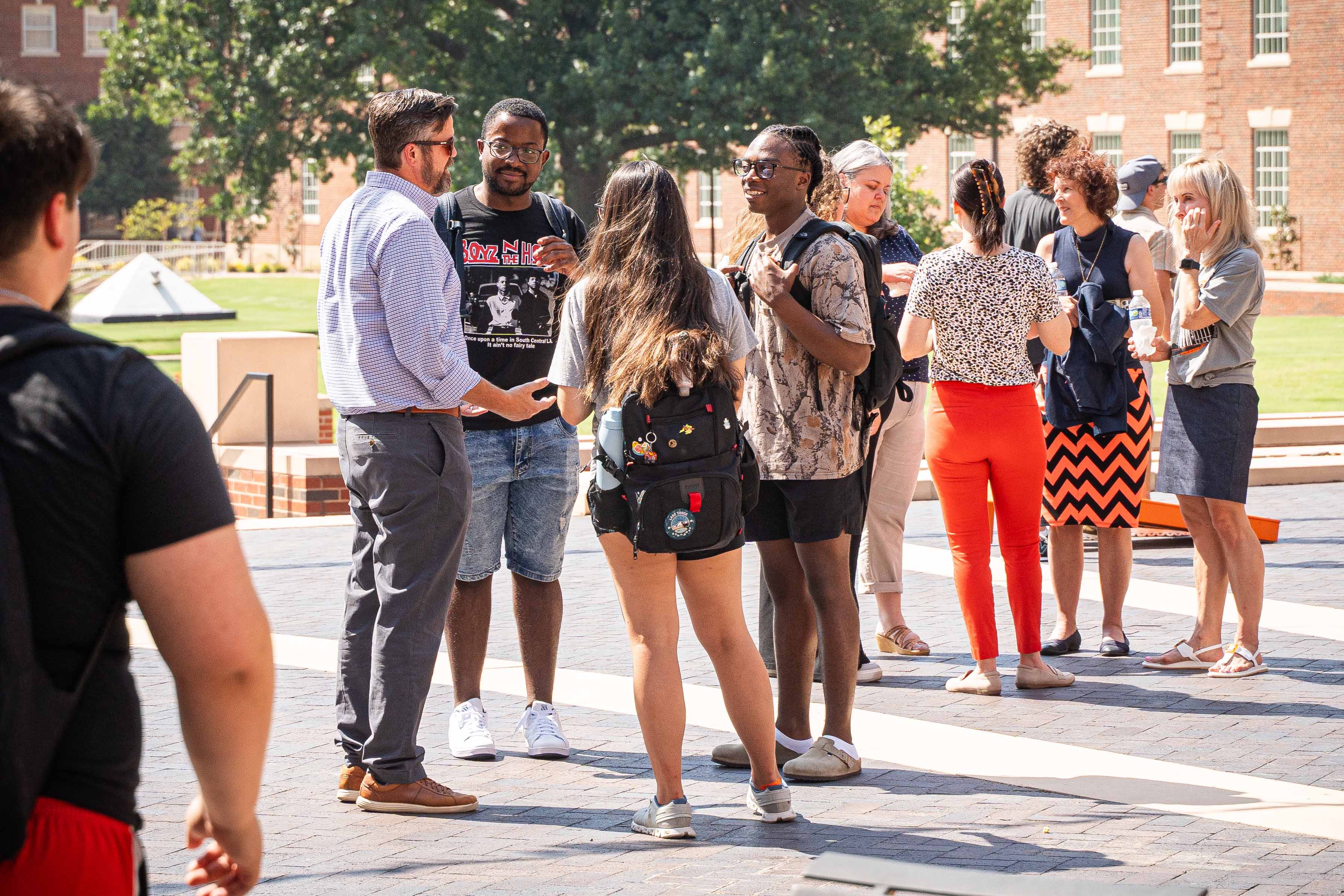 Students speaking to professor in the Business Building courtyard.