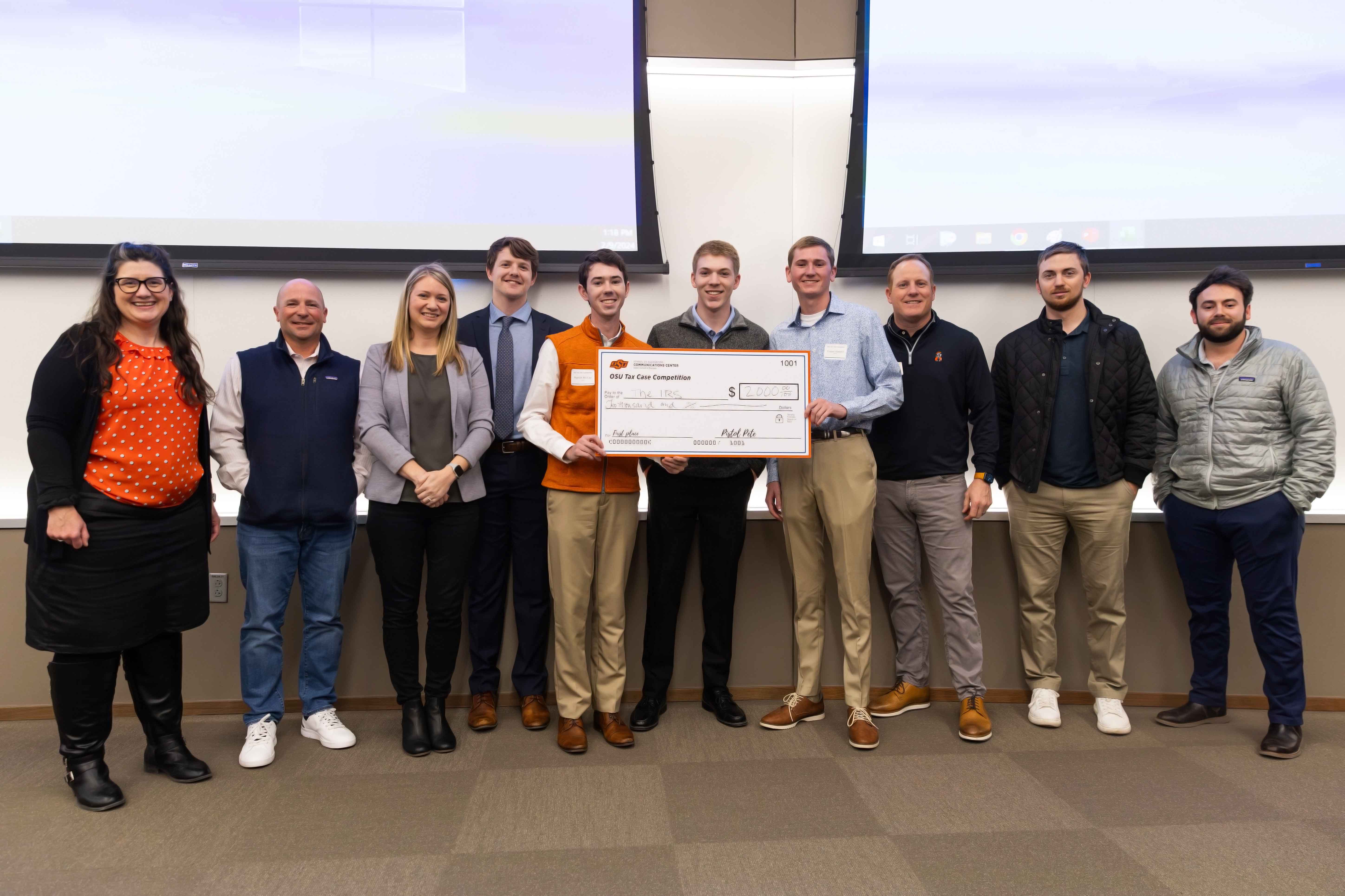 Finance competition winners holding check for $2,000. 8 students with faculty.