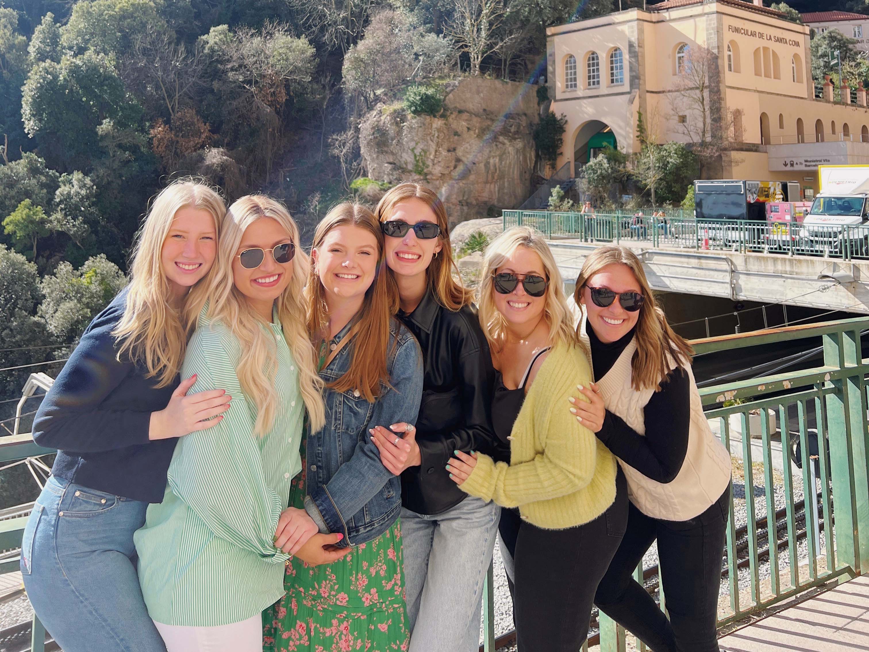 Group of female students embracing and smiling in front of a mountain in Barcelona.