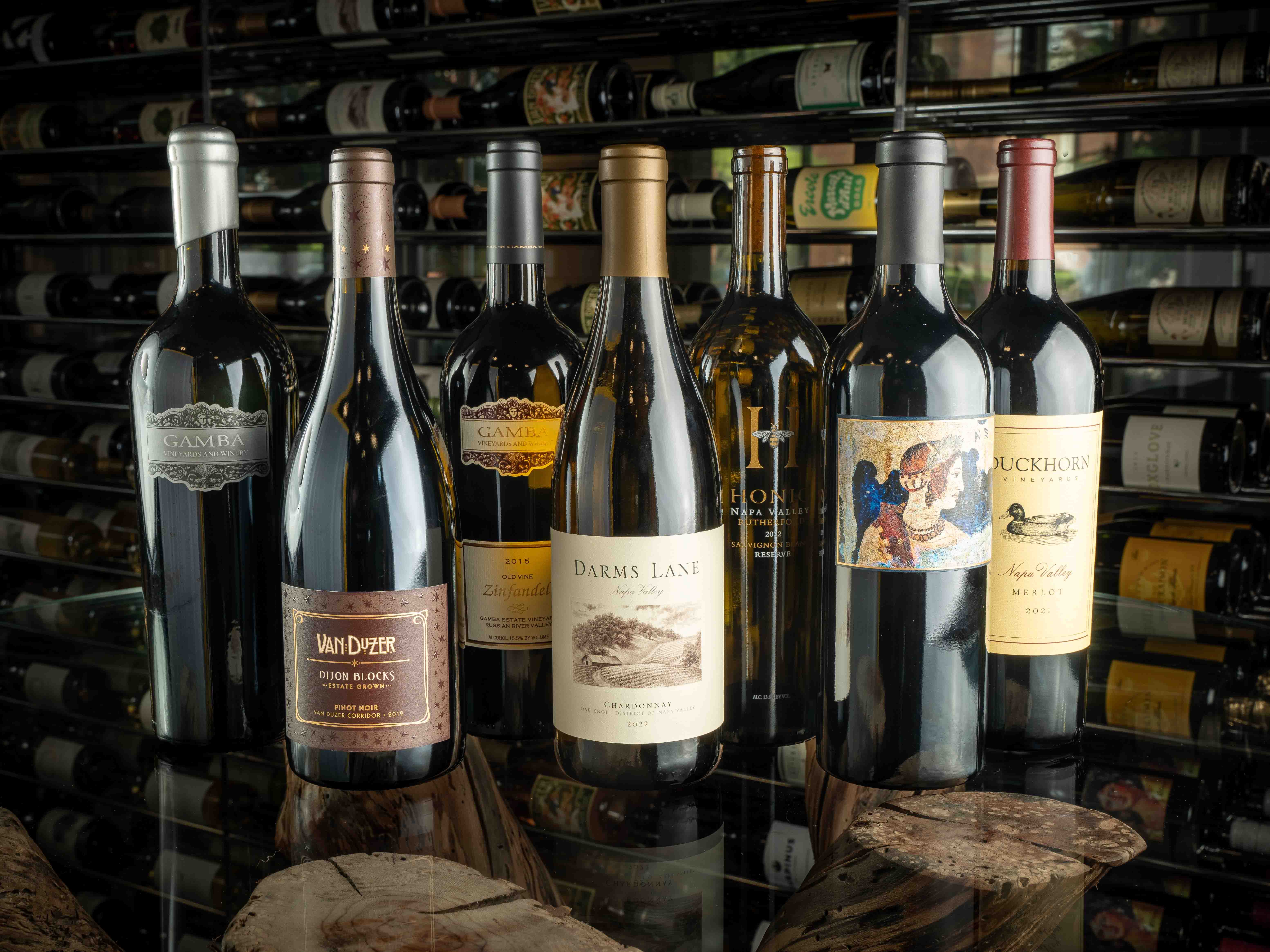 Wine bottles on a glass table with a wine case in the background.