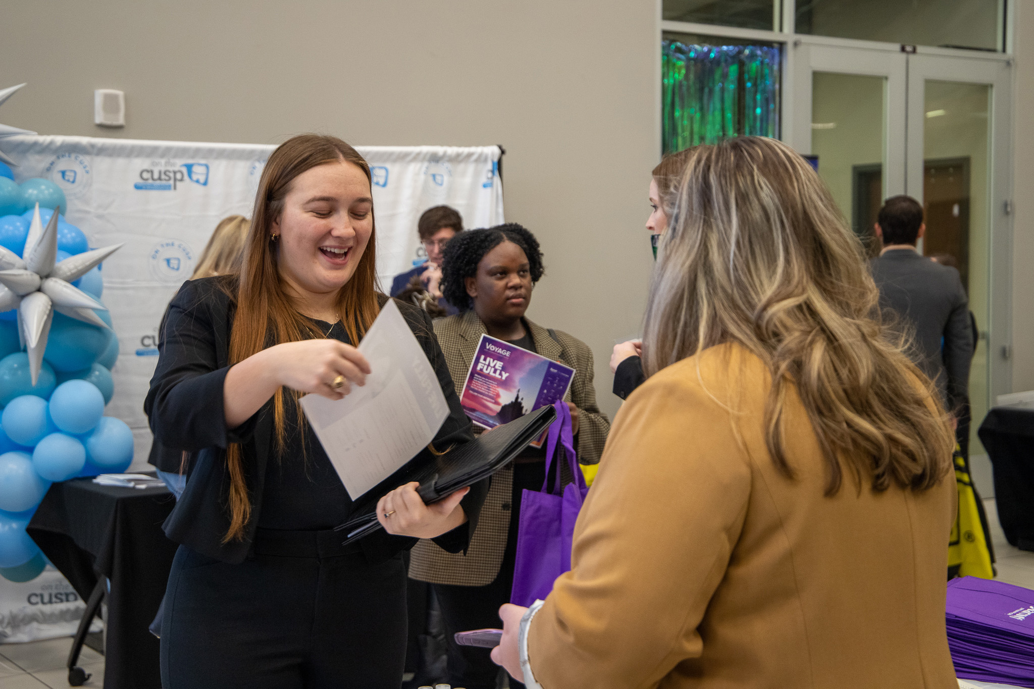Smiling female student handing her resume to a potential employer.