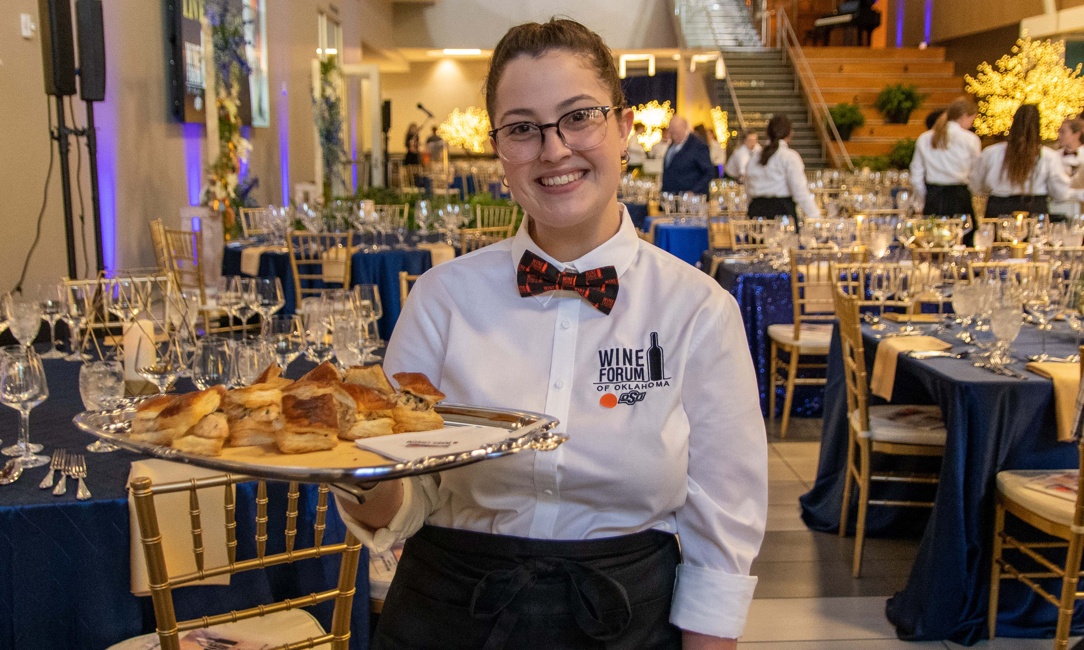 Student worker with a serving tray. gala dinner set up