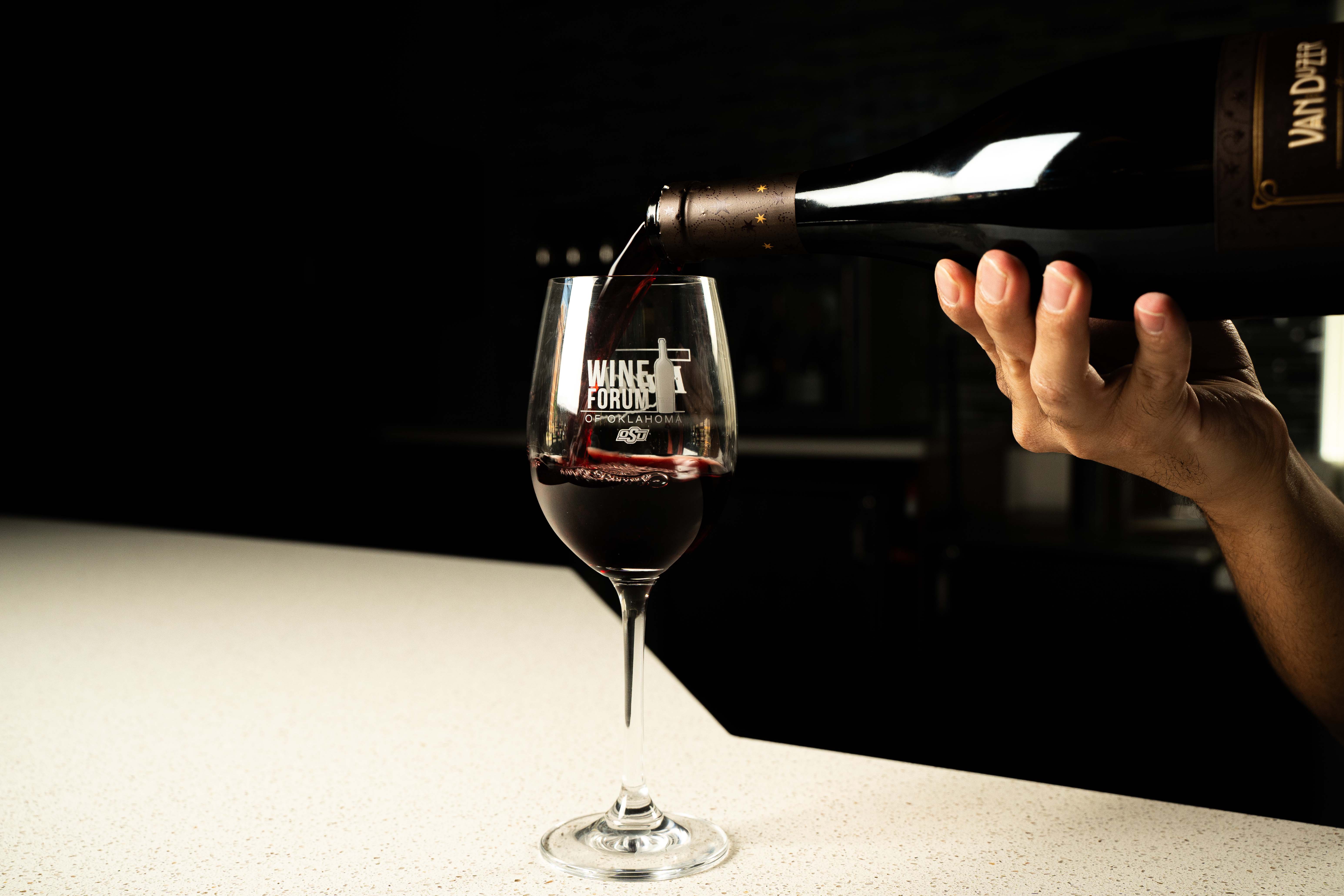 Wine being poured into bottle that says "Wine Forum 2025"
