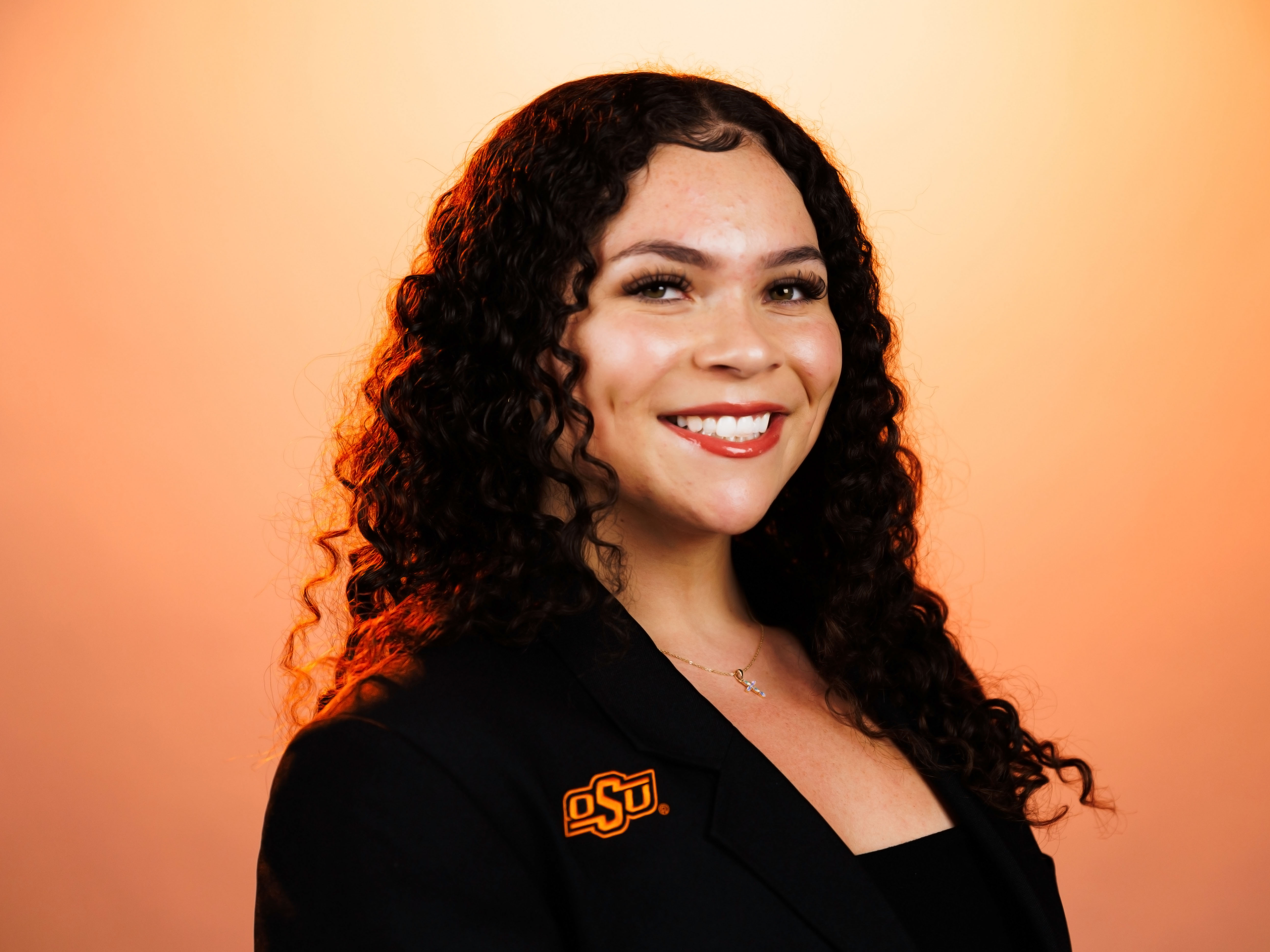Headshot of Brenda Tapia with an orange background.