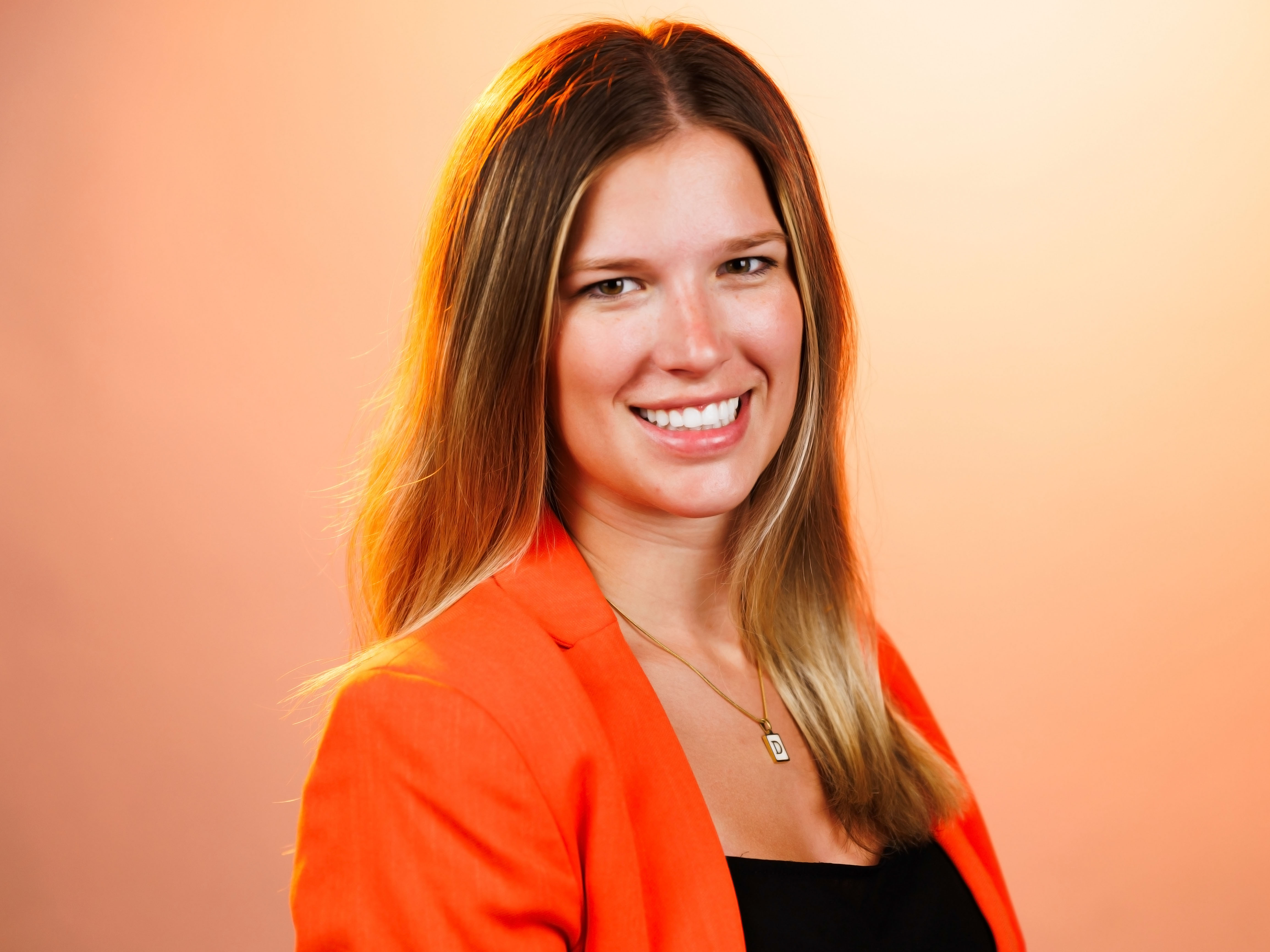 Headshot of Delaney with an orange background.