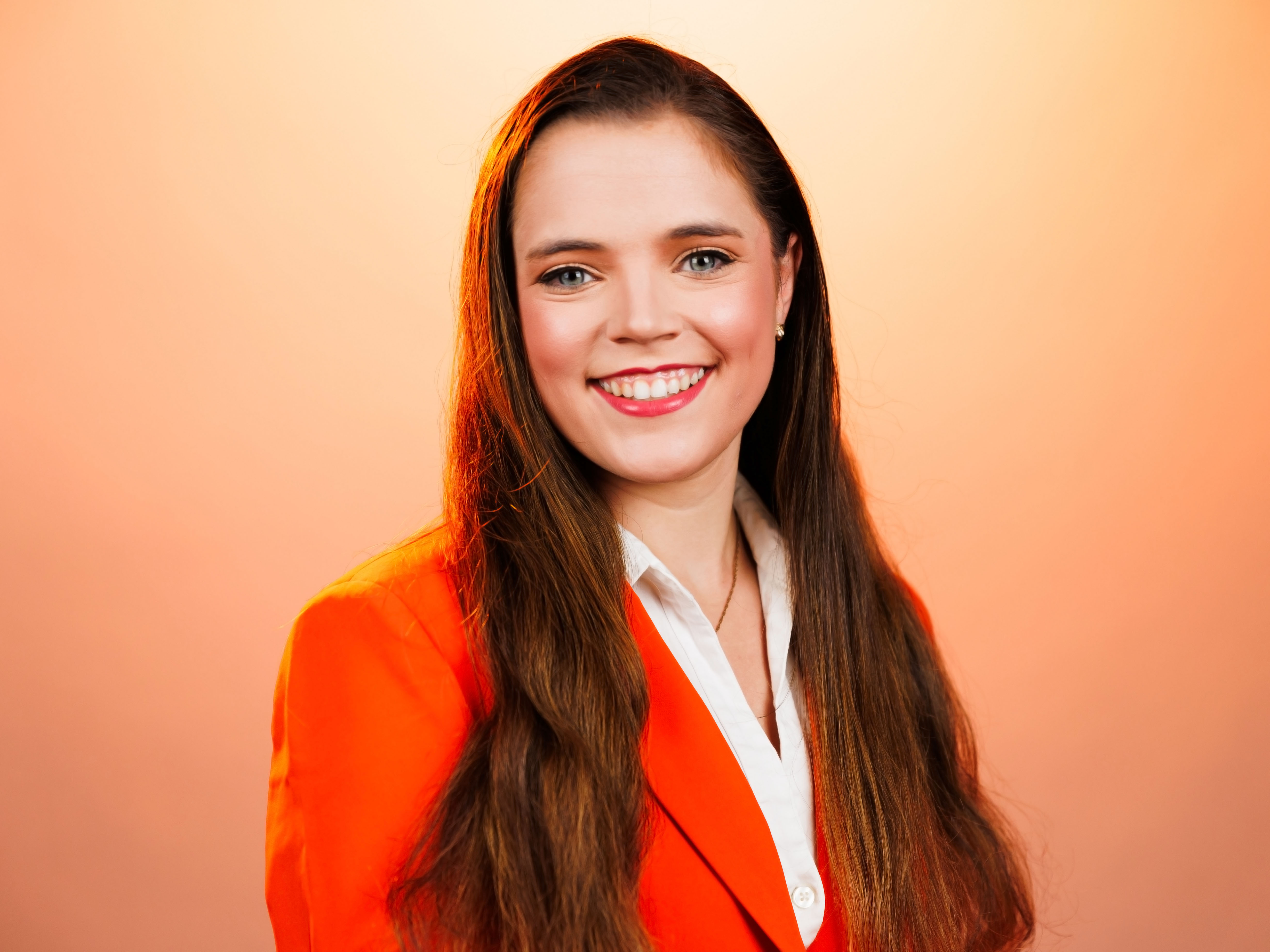 Headshot of Maci with an orange background.