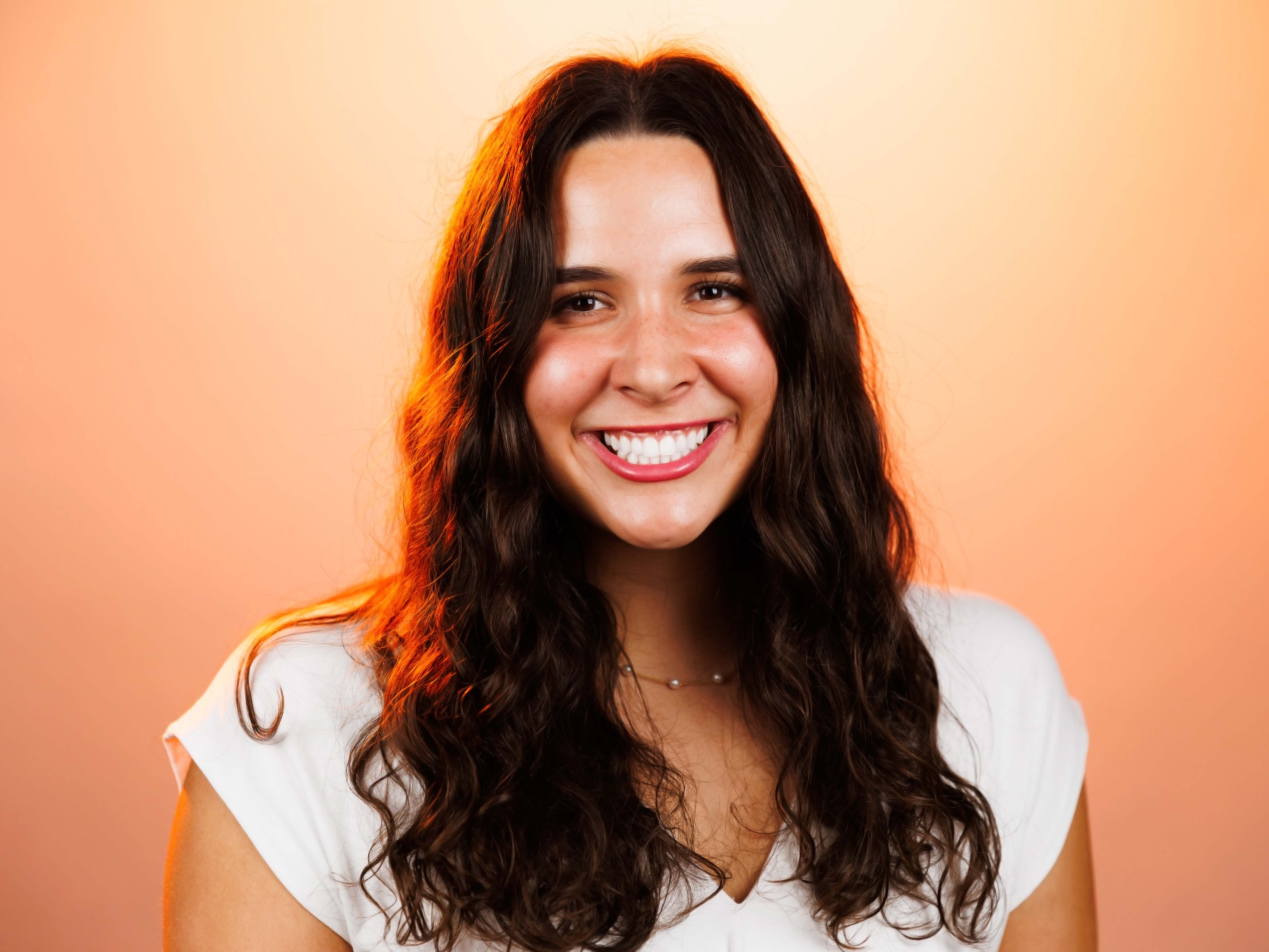 Headshot of RachelKate with an orange background.