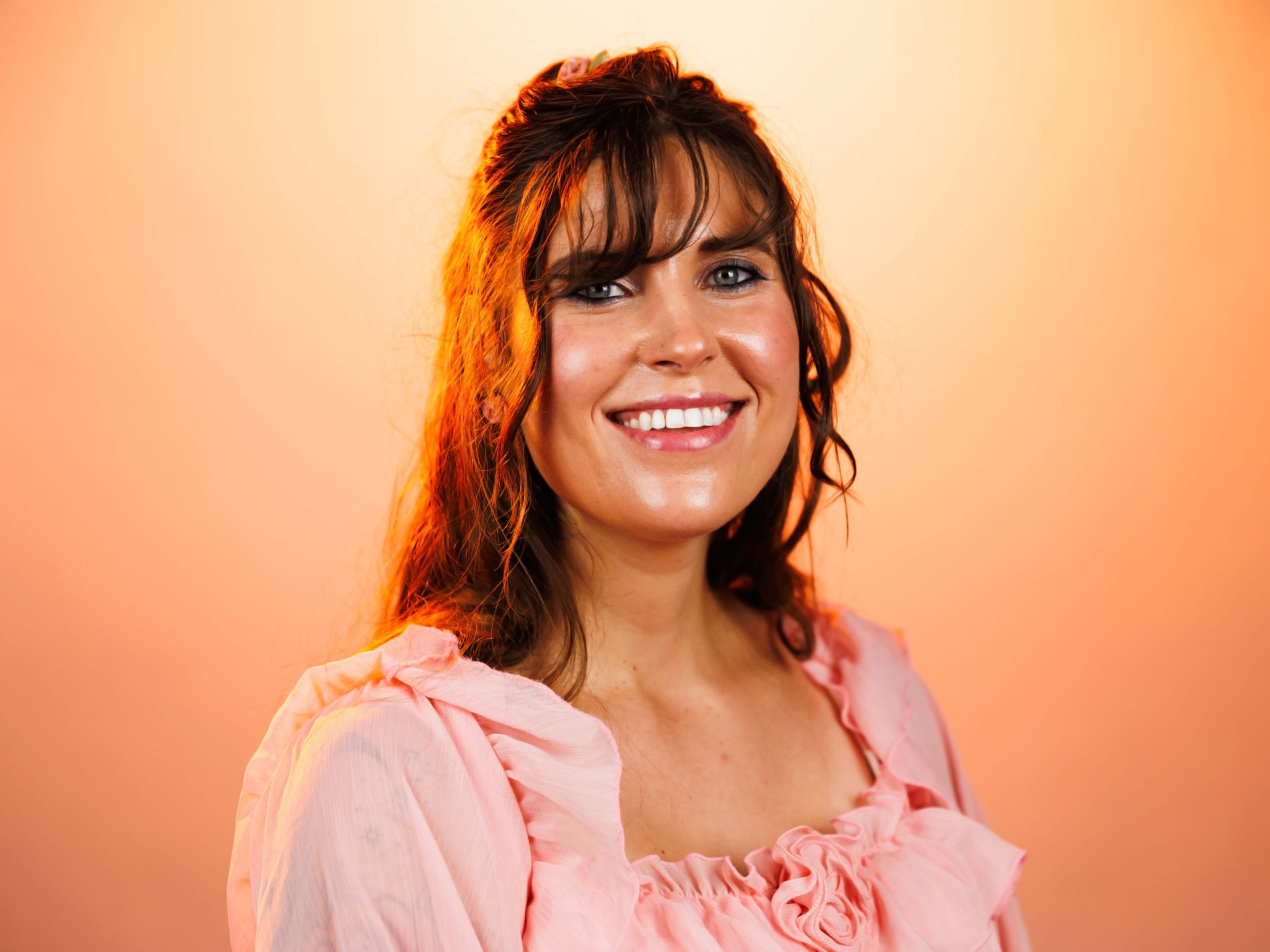 Headshot of Windsor Aniol with an orange background.