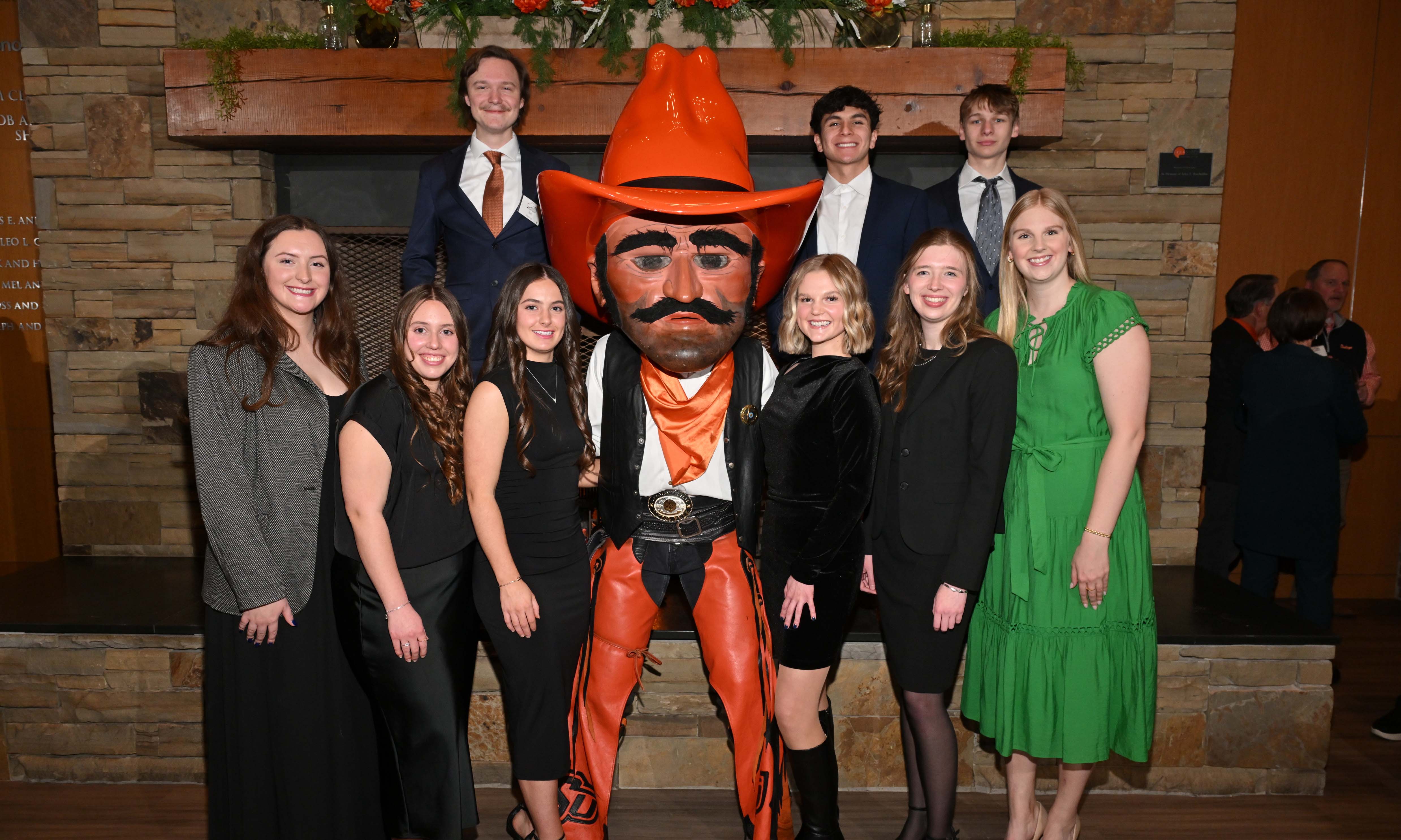 Group of students in formal attire posing with the Pistol Pete mascot.