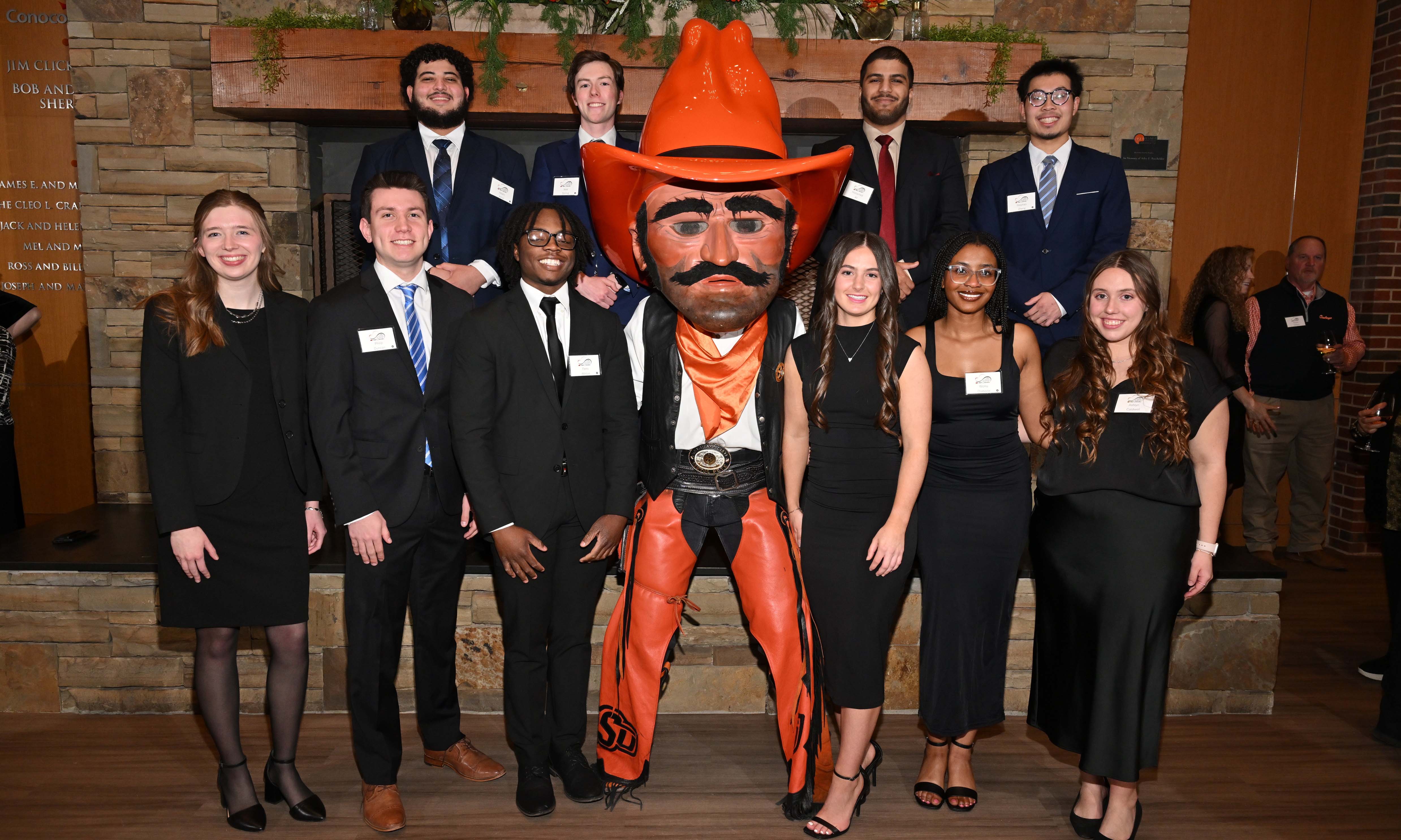 Group of students dressed professionally posing with the Pistol Pete mascot.