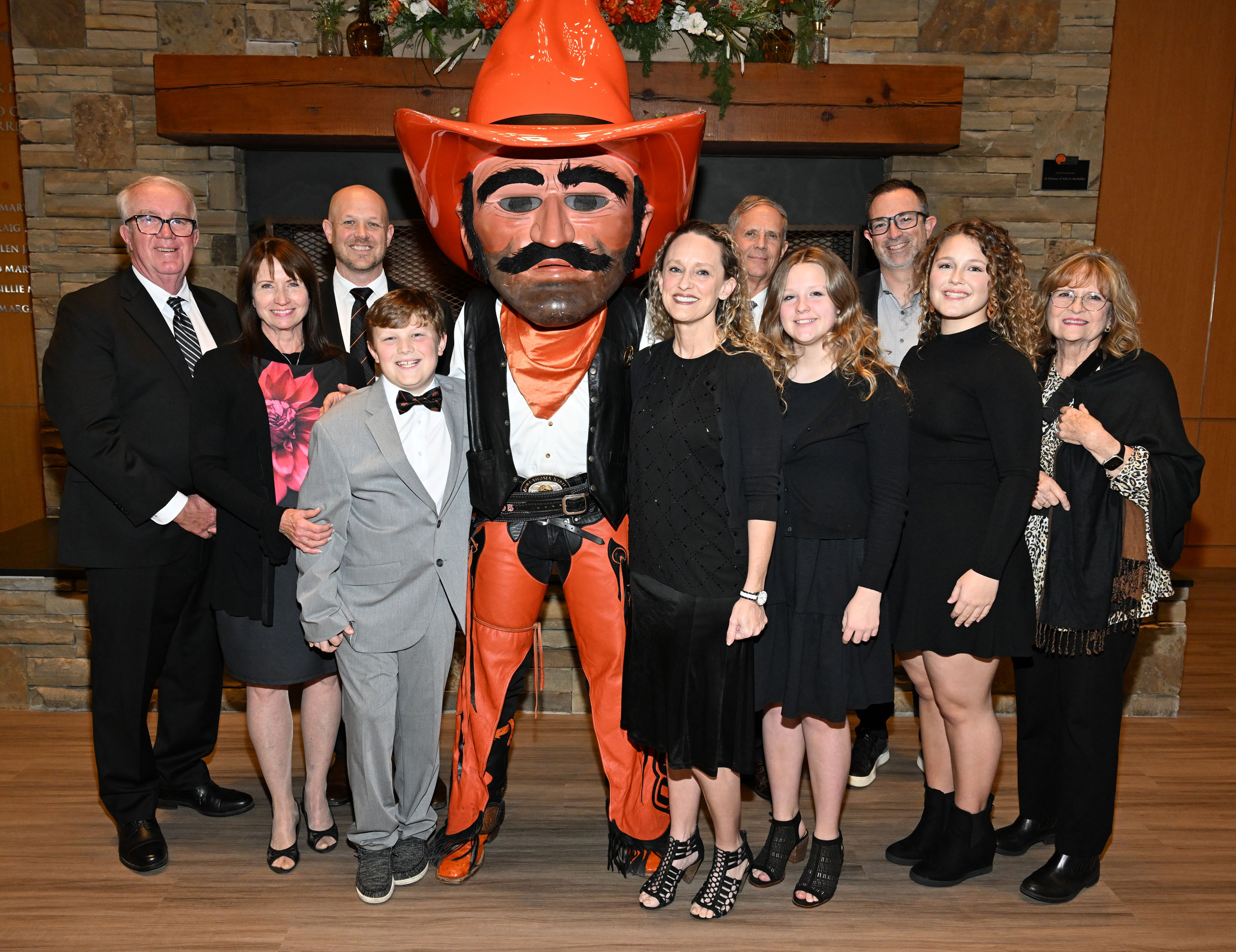 Award winner's large family smiling with Pistol Pete in alumni center lobby.