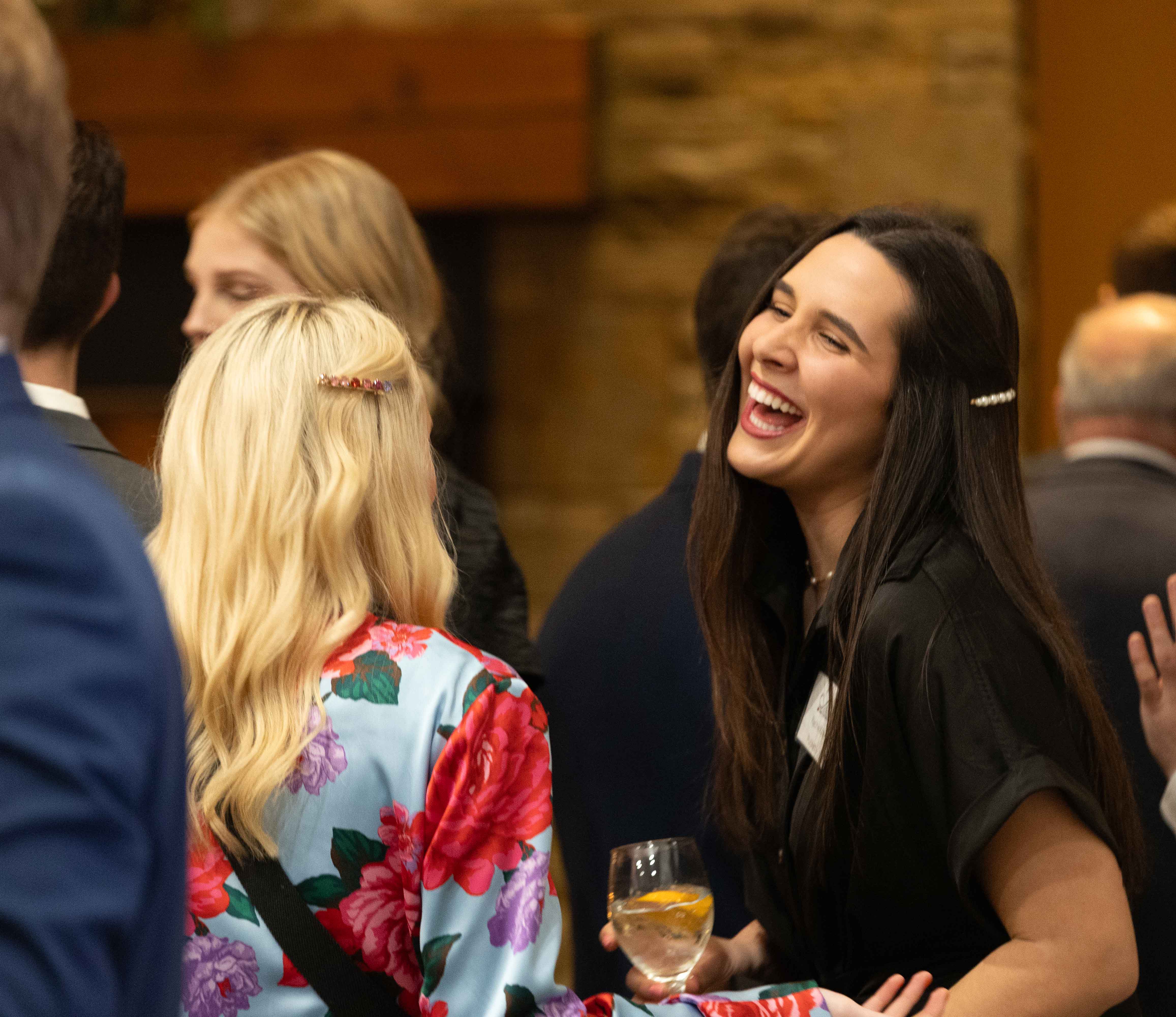 Female student dressed professionally speaking with someone and laughing in the lobby of the alumni center.