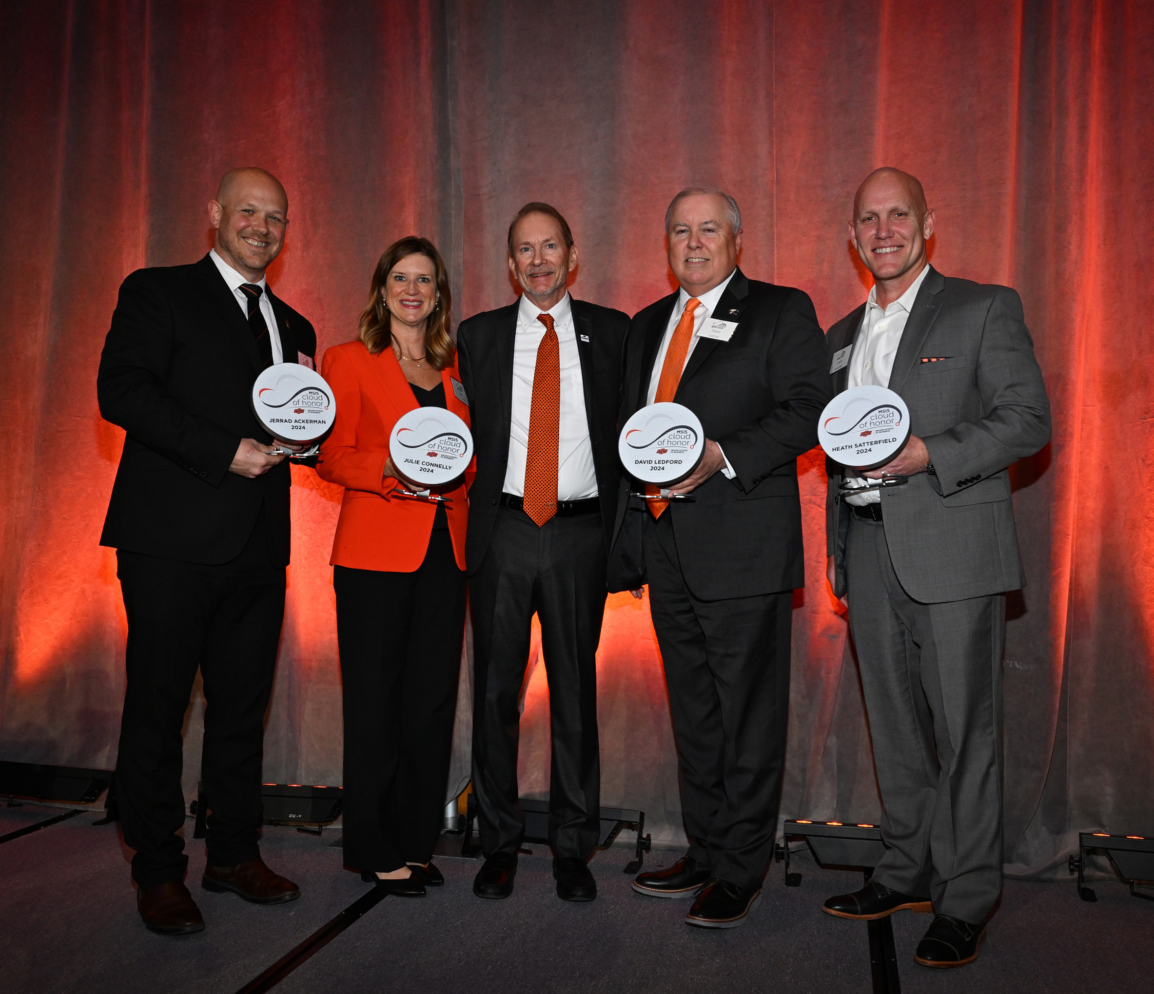 Cloud of Honor inductees standing on stage holding awards with Rick Wilson, dean of the School of Management Information Systems