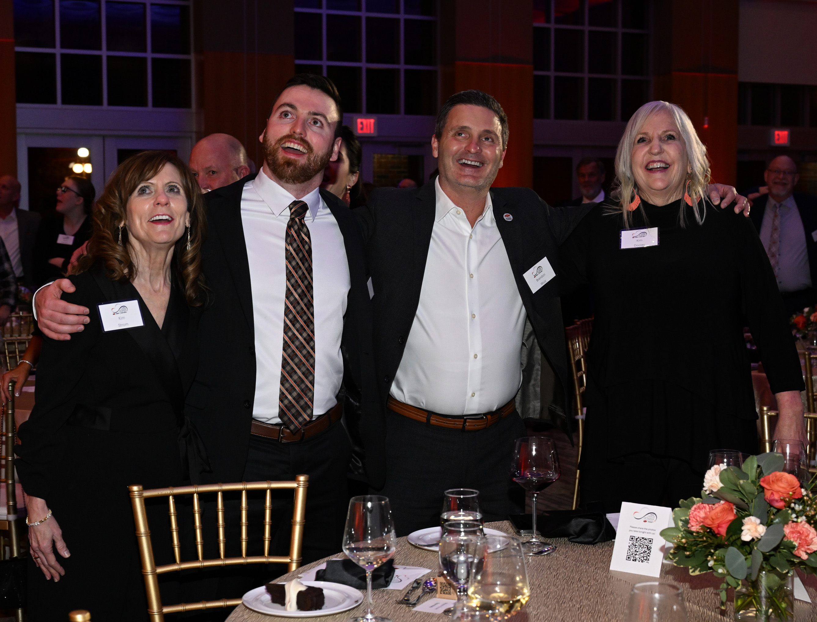 Four people standing and smiling singing the alma mater song.