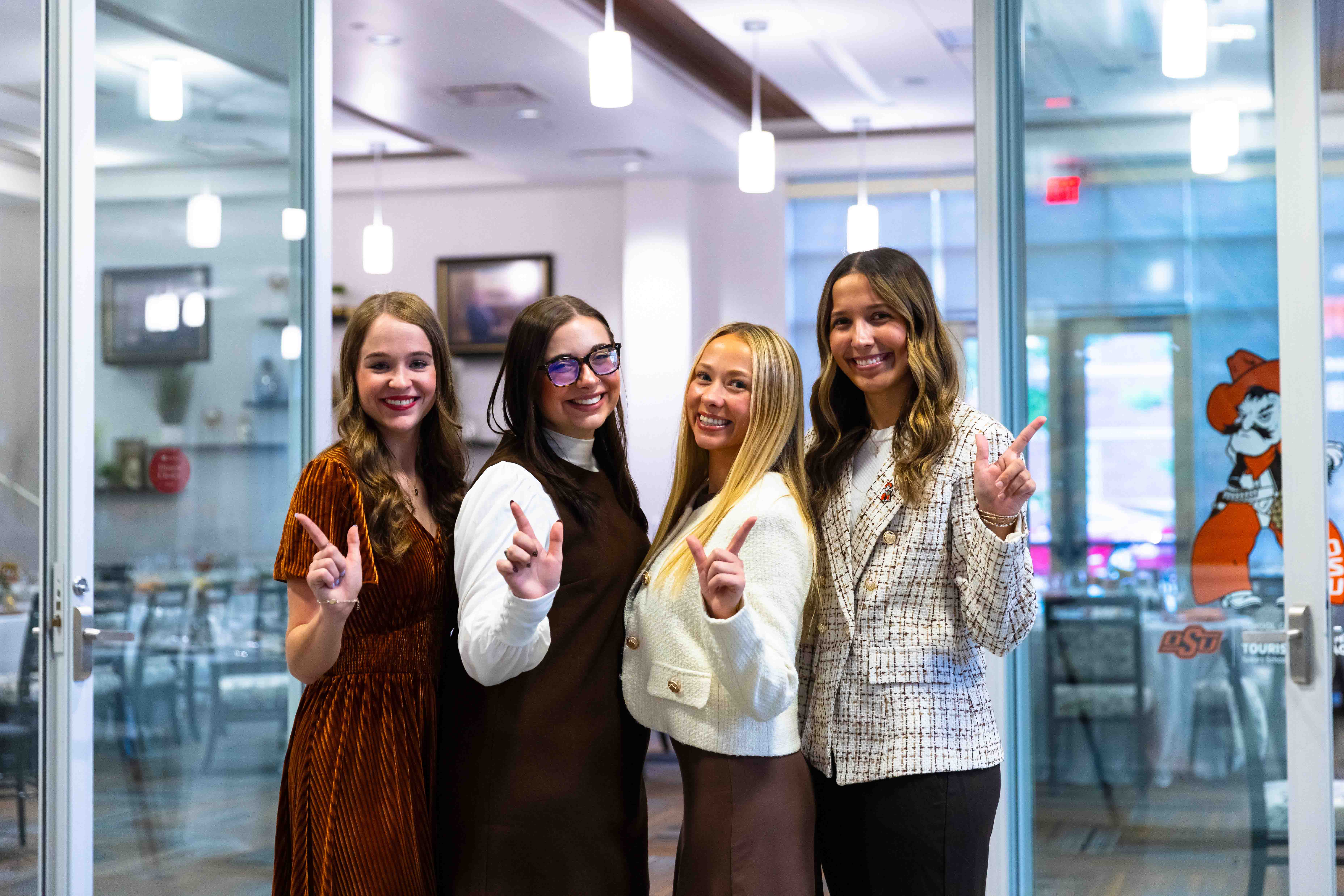 Female students dressed professionally hold up a "go pokes!"