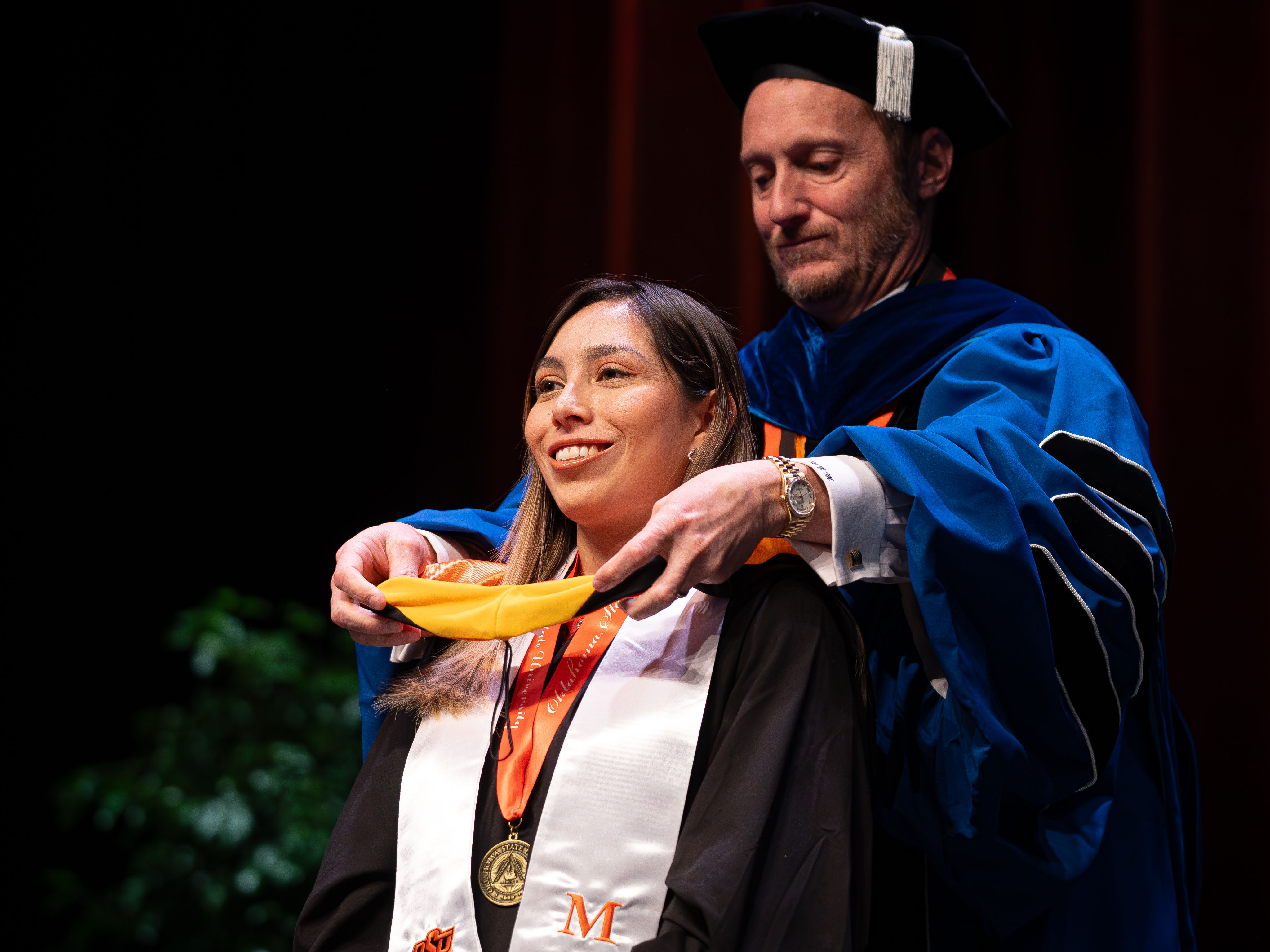 Female student receiving her graduate hood during a ceremony.