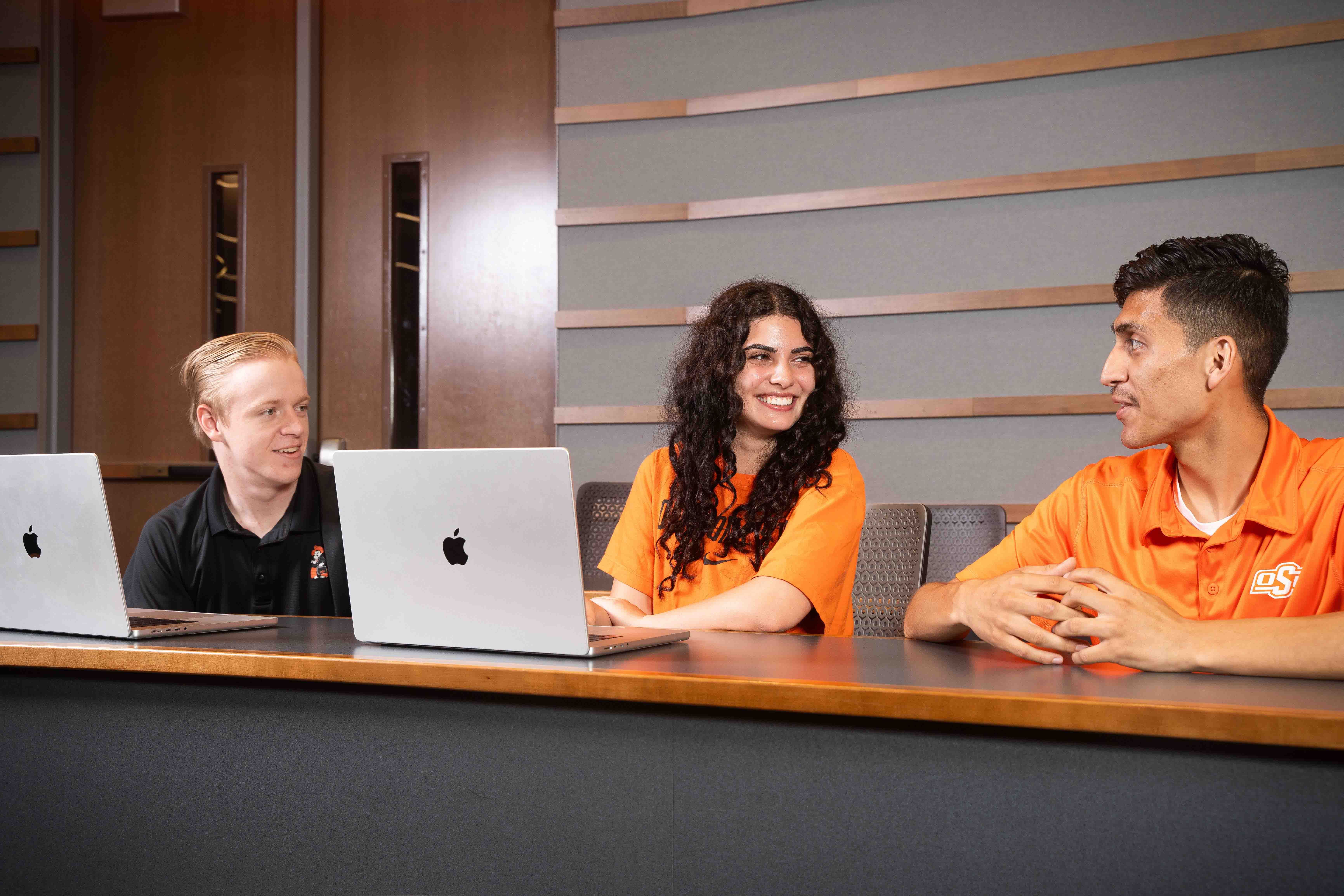 Three students working on a group project smiling in a classroom